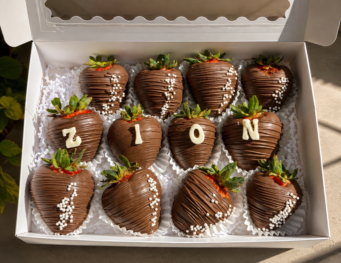 Dozen milk chocolate covered strawberries personalized with the name ZION in white chocolate letters